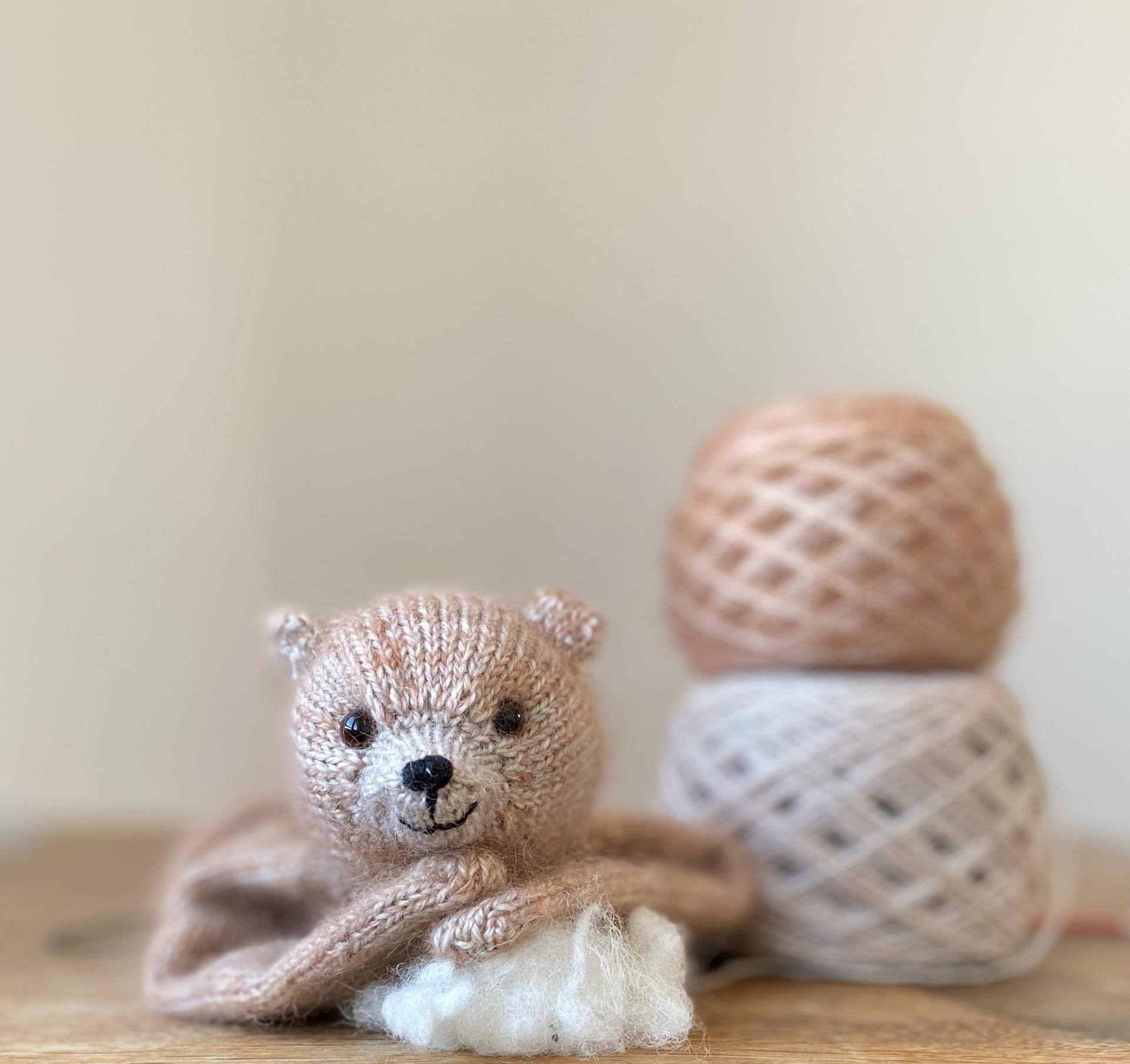 Peach knitted bear and yarn