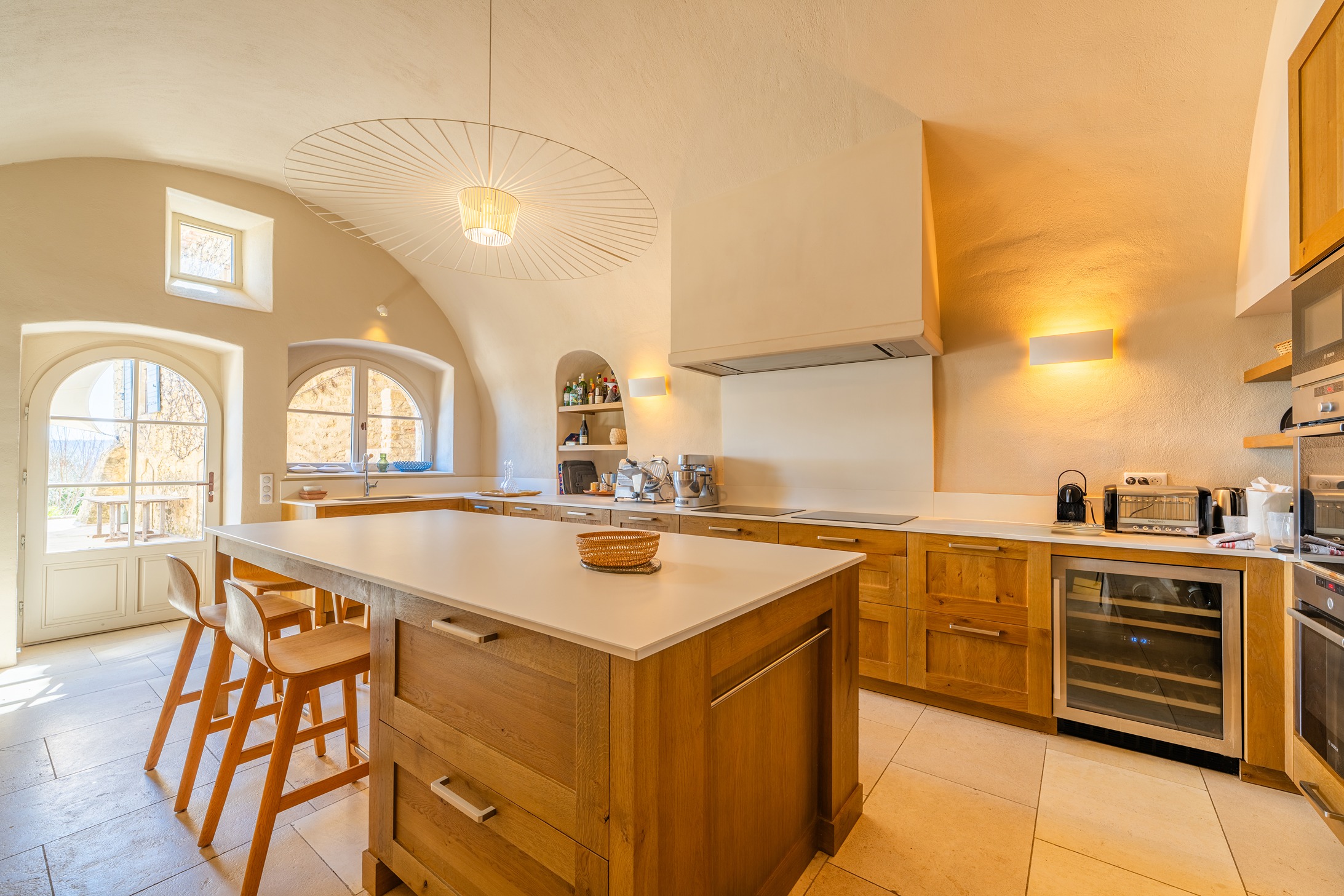 Kitchen area with various appliances and highchairs for the kitchen island.