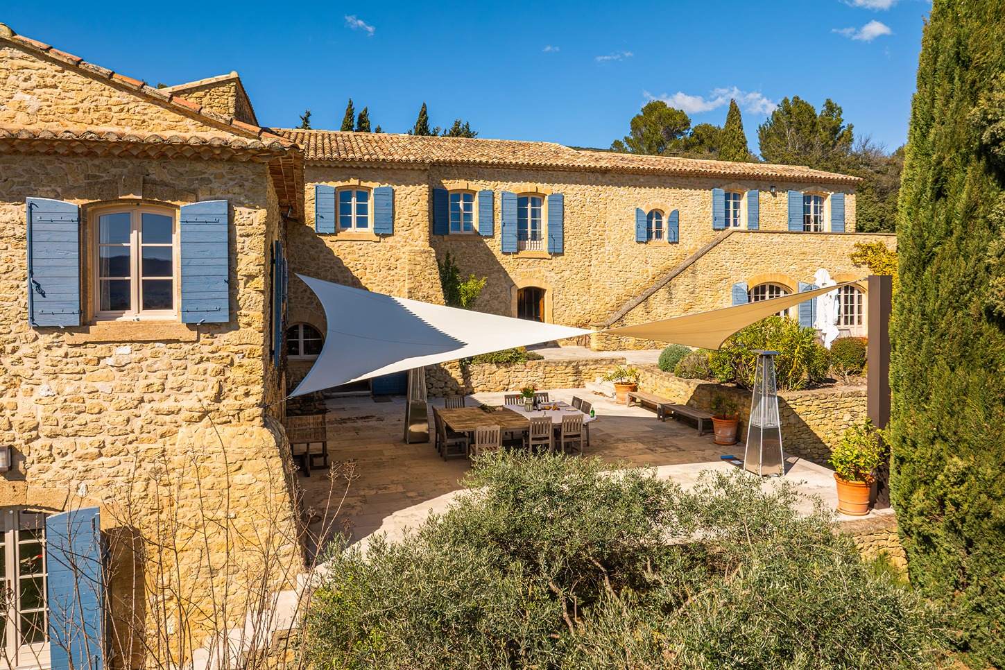 Outside sitting area in a courtyard with lots of shade with house in the background.
